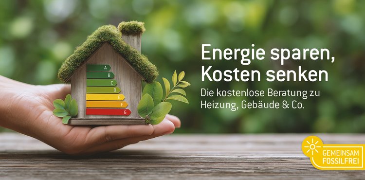 Hand die ein Haus in der Hand hält mit einer Energieskala drauf. Im Hintergrund grüne Blätter