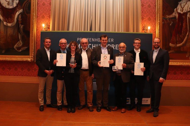 Gruppenfoto der Gewinner des Klimaschutzpreises 2019. 6 Gewinner und Herr Herker und Herr Andreas Herschmann stehen auf der Bühne im  Festsaal des Rathauses. Die Gewinner halten die Preise und die Urkunden in die Höhe.