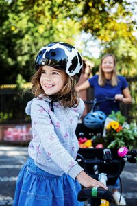 Mädchen steht mit dem Fahrrad, Mutter im Hintergrund