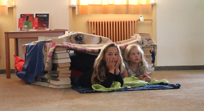 So lässt es sich aushalten: Die Kinder lauschen in ihrer selbstgebauten Bücherhöhle der spannenden Geschichte