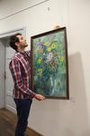 Fabian Langenecker, Praktikant der Kulturabteilung der Stadtverwaltung Pfaffenhofen, hängt das Ölbild „Blumenstrauss“ von Siegfried Braun in die Ausstellung.