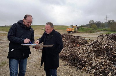 Andreas Herschmann (Vorstand der BEG PAF) 
und Markus Käser (Vorsitzender Bürgerenergie Bayern e.V.) vor der ehemaligen Kiesabbaufläche auf welcher der Bürgersolarpark errichtet werden soll.