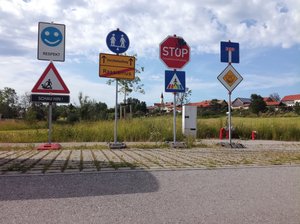 Verkehrsschilder auf einem Parkplatz vor einer Wiese