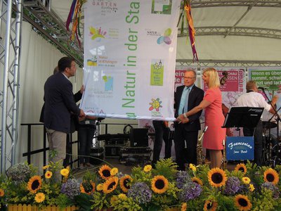 Übergabe der Gartenschau-Fahne an die nächste Gartenschau "Natur in Wassertrüdingen 2019". Von rechts: Thomas Herker, Günther Babel (Erster Bürgermeister von Wassertrüdingen) und Ulrike Scharf