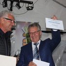Florian Weiß (rechts) überreicht Vorsitzenden Sigmund Busch eine Urkunde und einen Gutschein zum Kauf von Sportgeräten.
