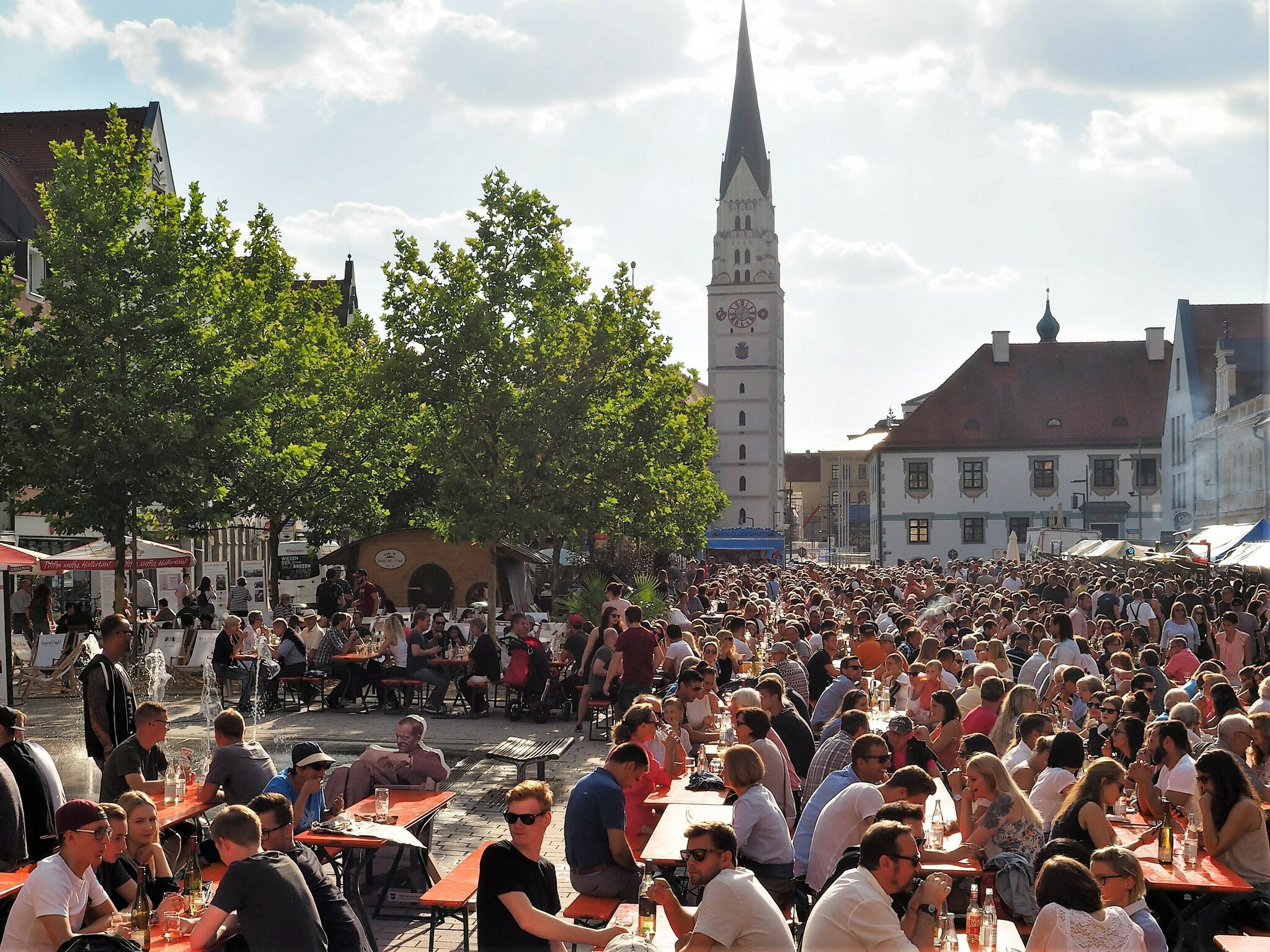 Menschen auf Bierbänken auf dem Hauptplatz
