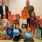 Die Burzlbaam-Kinder freuen sich mit ihrem Kita-Leiter Tobias Jobst (hinten rechts) über die Spende, die Debeka-Geschäftsstellenleiter Marcus Brück überreichte.