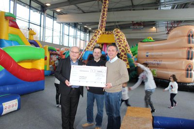 Scheckübergabe im Hüpfburg-Paradies in der Niederscheyerer Mehrzweckhalle mit (von links): Sparkassen-Vorstandsmitglied Stefan Maier, Norbert Kurzmeier von der Kuno GmbH und Bürgermeister Thomas Herker.