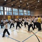 Mädchen, Buben, Frauen und Männer sind mit Konzentration, Eifer und Spaß beim Kung Fu-Training.