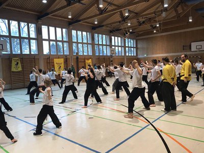 Mädchen, Buben, Frauen und Männer sind mit Konzentration, Eifer und Spaß beim Kung Fu-Training.