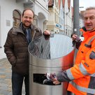 Andreas Herschmann (links), Klimaschutzreferent des Stadtrats, und Stefan Maier von den Stadtwerken an einem der neuen Hightech-Abfalleimer auf dem Hauptplatz.