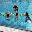 Schwimmmeister Tolga Ucak bei seinem Kinderschwimmkurs im Freibad Pfaffenhofen. Mit großer Begeisterung sind die kleinen Schwimmerschüler/innen bei der Sache.  Trotz aller Späße, hier wird auch fleißig trainiert. Denn nach 10 Schwimmkursstunden soll sich jeder freuen: “Ich kann schwimmen! Ich habe das Seepferdchen!”