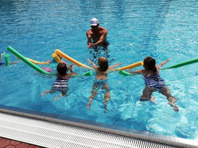 Schwimmmeister Tolga Ucak bei seinem Kinderschwimmkurs im Freibad Pfaffenhofen. Mit großer Begeisterung sind die kleinen Schwimmerschüler/innen bei der Sache.  Trotz aller Späße, hier wird auch fleißig trainiert. Denn nach 10 Schwimmkursstunden soll sich jeder freuen: “Ich kann schwimmen! Ich habe das Seepferdchen!”