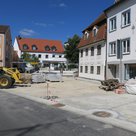 Arbeiten an der Auenstraße mit gelben Bagger links, Pflastersteinen in der Mitte und Häuserfassaden