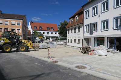 Arbeiten an der Auenstraße mit gelben Bagger links, Pflastersteinen in der Mitte und Häuserfassaden