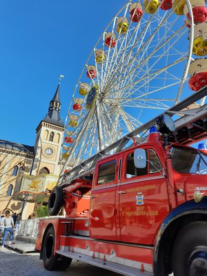 Die "Oide Lies", der rote Feuerwehr-Oldtimer der Feuerwehr Pfaffenhofen auf dem Hauptplatz. Dahinter das Rathaus und das Riesenrad.