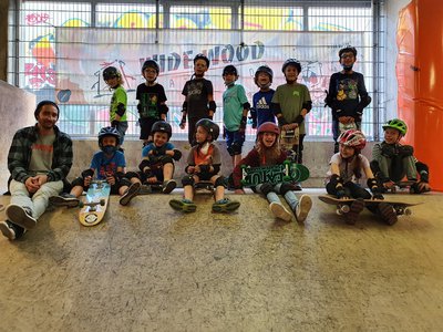 Skateboard-Workshopleiter mit 13 Kindern auf Skaterampe in der Skatehalle