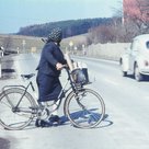 Eine Frau mit Fahrrad überquert in Haimpertshofen die Straße im Jahr 1971.