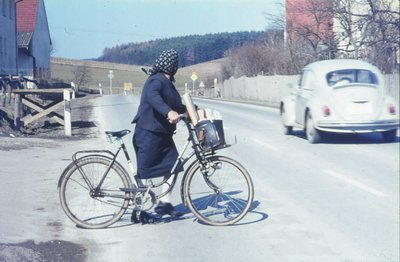 Eine Frau mit Fahrrad überquert in Haimpertshofen die Straße im Jahr 1971.