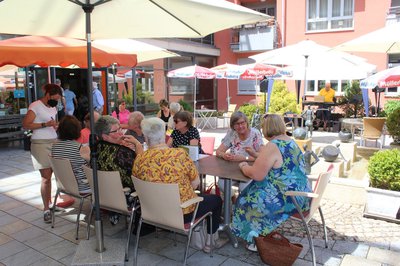 Besucherinnen und Besucher sitzen bei Sonnenschein im Innenhof des Bürgerzentrums Hofberg.