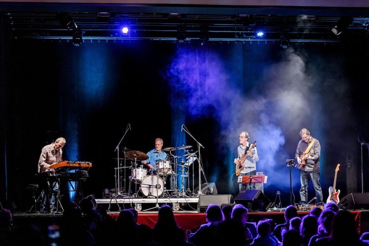 Band spielt auf einer Bühne, Publikum ist zu sehen