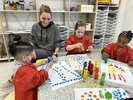 Kinder in Kitteln beim Malen, Erziehern hilft