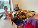 Zwei Kinder sitzen auf dem Boden und spielen mit Holzbauklötzen.