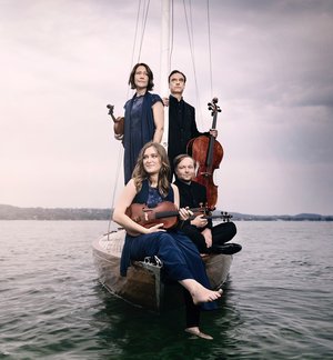 Das Quartett mit Instrumenten auf einem Boot auf dem Wasser.
