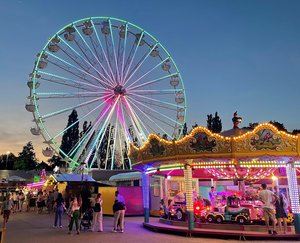 Das leuchtende Riesenrad und das Karussell in der Dämmerungsstimmung