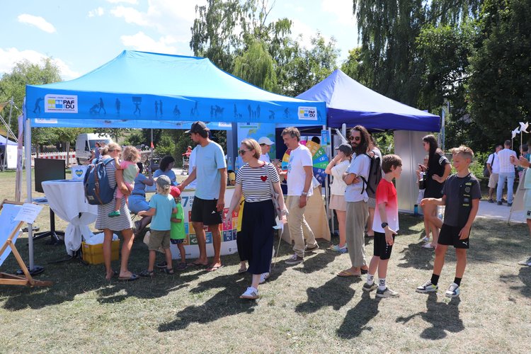 An einem Pavillion treffen sich viele Leute.