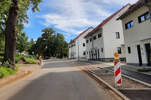 Straße in Streitdorf ohen Asphaltschicht und neu angelegten Gehwegen.