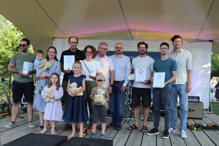 Auf der Bühne stehen viele Leute mit Ihren Urkunden.
