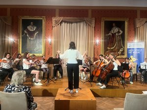 Festsaal; auf der Bühne Schüler mit Instrumenten und eine Lehrerin