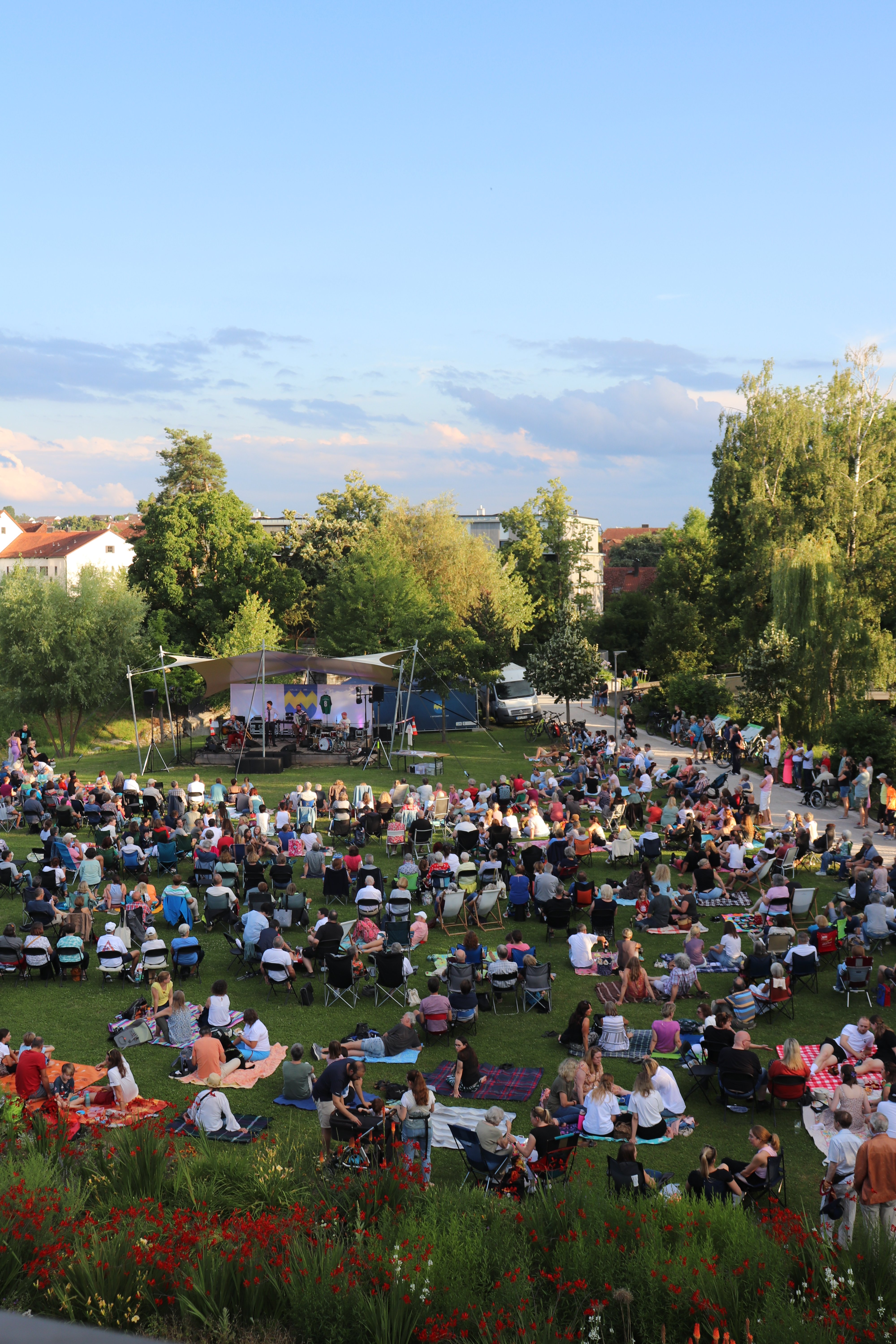 Bürgerpark mit vielen Menschen, Bühne mit Musiker.