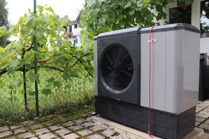 Wärmepumpe steht neben dem Garten auf einer versiegelten Fläche