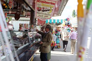 Ältere Menschen kaufen am Süßigkeitenstand auf dem Volksfest ein