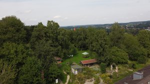 Luftaufnahme des Interkulturgartens mit vielen Bäumen, rasenfläche, einer GArtenlaube mit Ziegeldach und einem bepflanzten Hang