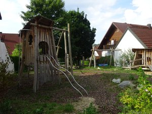Spielplatz mit Kletterturm, Schaukel, grünem Gras