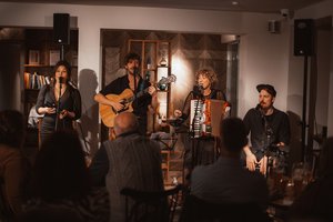Band auf einer Bühne mit Gästen