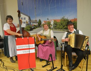 Hopfberg Trio mit Instrumenten und in Tracht auf einer Bühne