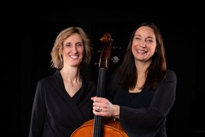 Zwei Frauen vor schwarzem Hintergrund mit Cello