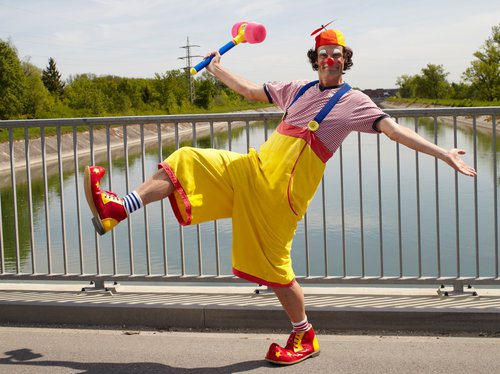 Ein bunt gekleideter Clown auf einer Brücke