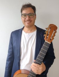 Cristian Adrian Milesi hält eine Gitarre in der Hand und schaut in die Kamera
