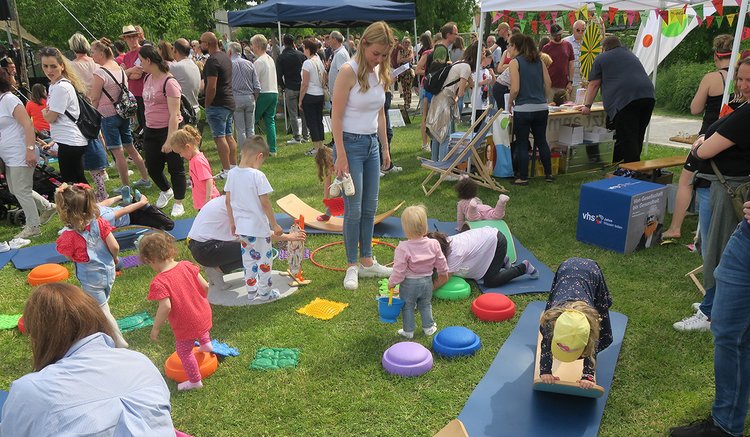 Kinder spielen mit ihren Eltern auf dem Gras im Bürgerpark.