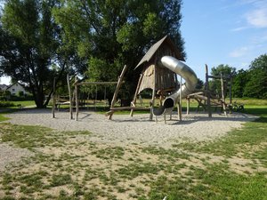 Spielplatz mit Kletterturm aus Holz und Rutsche im Grünen