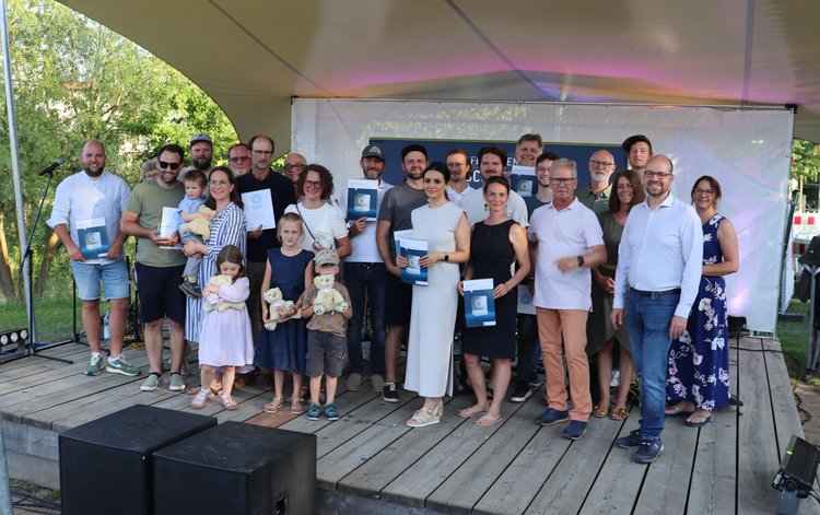 Auf der Bühne stehen viele Leute mit Ihren Urkunden.