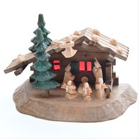 Kleine Krippe mit Haus, Tannen und kleinen Holzfiguren.