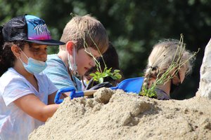 Drei Kinder bauen aus Sandhügel ein Sandarium