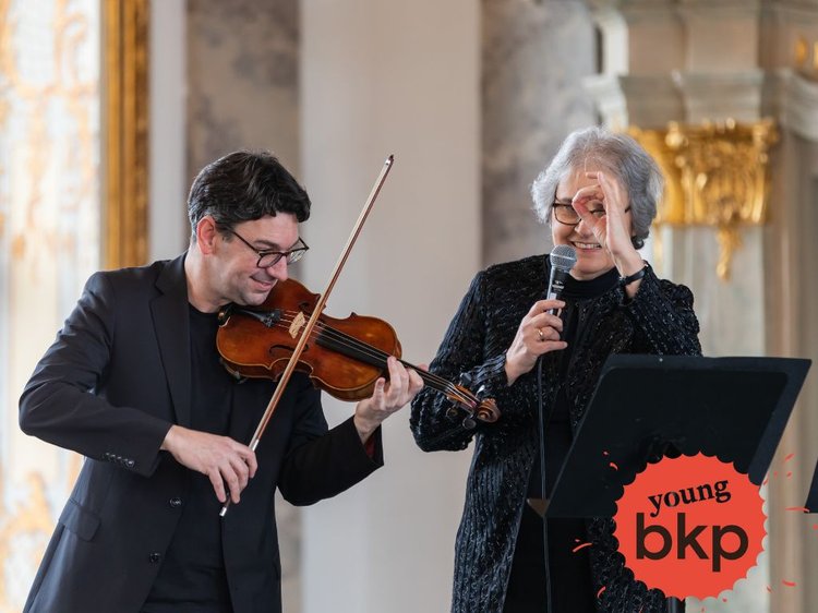 Valentin Holub und Dr. Stefana Titeica an Mikrofon und Violine, in schwart gekleidet.