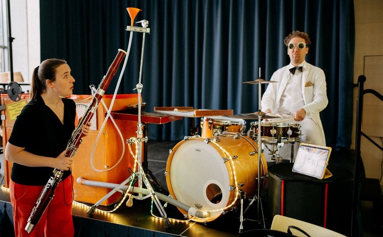 Ingrid Hausl mit Instrument an der Bühne und schaut einen Mann als Professor verkleidet erstaunt an